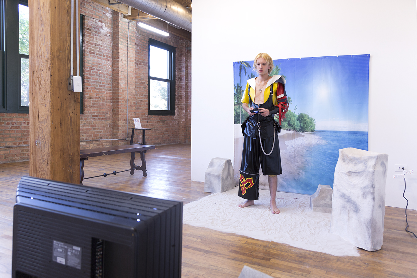 3/4 shot of Jesse dressed in cosplay playing video games on an artificial beach set